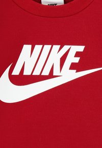 T-shirt de algodão vermelha com um grande logo branco da Nike com design em swoosh e um clássico decote redondo.