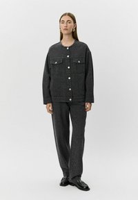 Siva denim jakna z leopardjim vzorcem, ki ima dve sprednji žepni in srebrne gumbe. V kombinaciji z ujemajočimi se hlačami in črnimi čevlji.