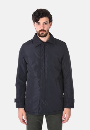 Giacca impermeabile blu navy con colletto a punta, chiusura frontale, due tasche laterali e polsini regolabili. Texture liscia e lucida.