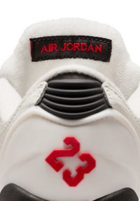 Λευκή φτέρνα αθλητικού παπουτσιού Air Jordan με κόκκινο "23" και μαύρη ετικέτα με την επιγραφή "AIR JORDAN" στο επενδεδυμένο λευκό κολάρο.