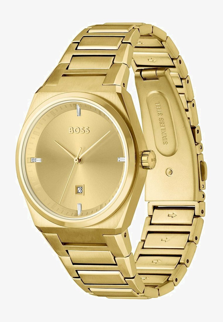 Reloj de acero inoxidable dorado con una esfera cuadrada, diseño minimalista y display de fecha a las 6 en punto. Presenta una pulsera de eslabones.