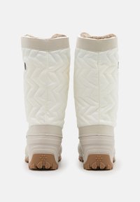 White quilted waterproof boots with beige rubber sole, textured upper, and fuzzy lining at the top. Traction outsole and logo detail.