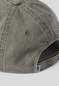 Zielona czapka z korduroyu o zaokrąglonej koronie, górnym guziku, otworach wentylacyjnych oraz regulowanym pasku z naszywką marki.