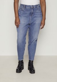 Bleka ljusblå jeans med avslappnad passform, utrustade med fem fickor och knappgylf, kombinerade med svarta snörstövlar med platå.