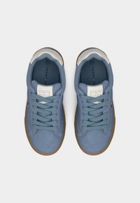 Μπλε σουέντ αθλητικά παπούτσια με λευκή λεπτομέρεια στη φτέρνα, με επίπεδα κορδόνια, υφή σόλας από καουτσούκ και ετικέτα με το λογότυπο στη γλώσσα.