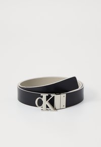 Zwarte leren riem met een zilveren metalen gesp die een prominent "CK"-logo heeft en een crèmekleurige binnenvoering. Gladde textuur, minimalistisch ontwerp.