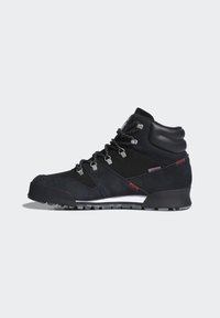 Wysokie buty trekkingowe z czarną zamszową powierzchnią, teksturowanym wykończeniem, srebrnymi detalami oraz kontrastującą białą podeszwą. Posiadają system sznurowania i akcenty.