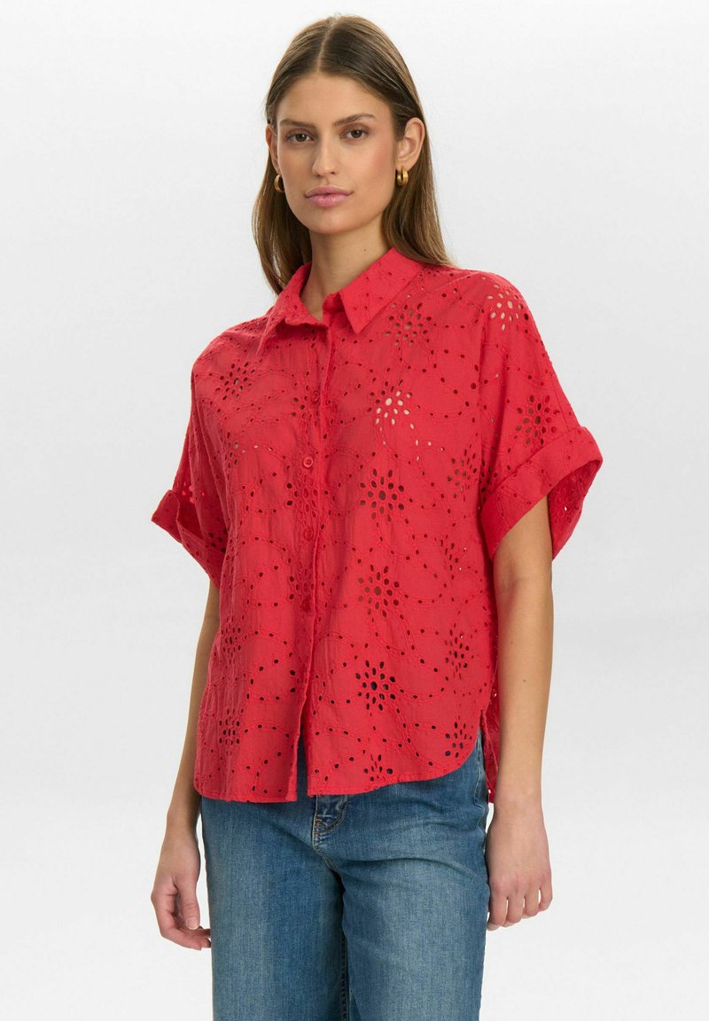 Red short-sleeve shirt with a button front, featuring cut-out patterns and a relaxed fit. Soft fabric with slight texture and rolled cuffs.
