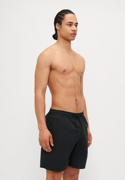 Shorts de bain noirs avec une taille élastique et un cordon de serrage, fabriqués à partir d'un matériau léger. Présente une texture simple et lisse.
