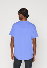 Μωβ t-shirt με χαλαρή εφαρμογή, κοντά μανίκια, στρογγυλεμένη βάση και διακριτική ραφή στο κέντρο της πλάτης. Μαλακή υφή υφάσματος.