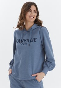 Blå hoodie i mjukt material med en avslappnad passform, med en dragsko i huvan och "AVENUE Paris" tryckt med mörka bokstäver. Långa ärmar.