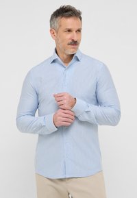 Camicia a maniche lunghe a righe blu chiaro e bianche con colletto a bottoni, vestibilità slim e polsini bianchi a contrasto. Tessuto morbido e design minimale.
