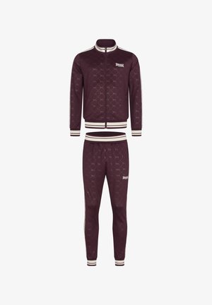 Tuta bordeaux realizzato in tessuto morbido, con un motivo a rombi, strisce bianche accentate, giacca con zip e pantaloni con vita elasticizzata.