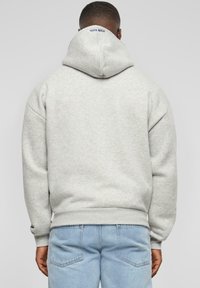 Felpa grigia con cappuccio realizzata in tessuto morbido, caratterizzata da una vestibilità comoda, polsini a costine e un logo ricamato sul collo.
