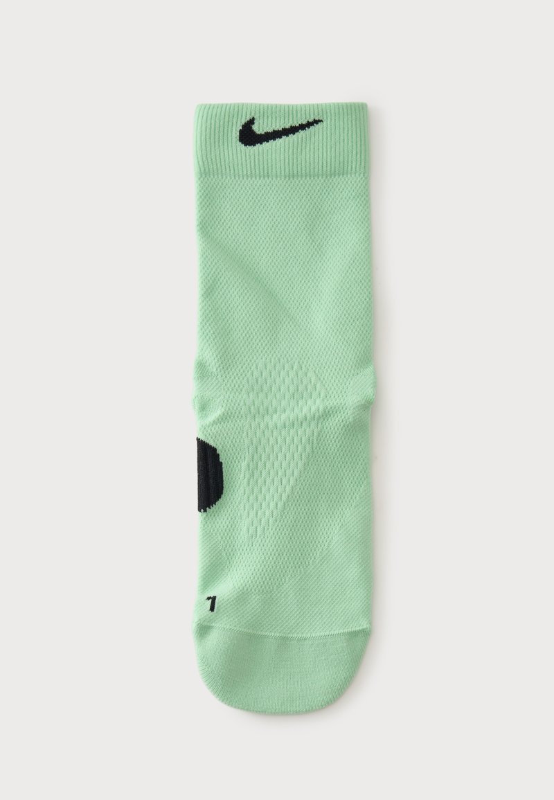 Κάλτσα Nike σε μέντα πράσινο με μαύρο λογότυπο swoosh κοντά στη μανσέτα και μαύρο σημάδι μεγέθους στην περιοχή του ποδιού, απεικονισμένη επίπεδη σε λευκό φόντο.