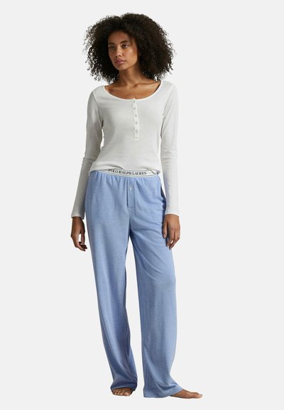 Bílý dlouhý rukáv s knoflíky, doplněný světle modrými pohodlnými kalhotami s logem na pásu. Hladký materiál a uvolněný střih.