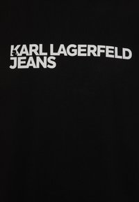 Fekete pamut póló, amelynek elején merész fehér felirat olvasható: "KARL LAGERFELD JEANS". Tiszta dizájn, matt felülettel és kerek nyakkal.
