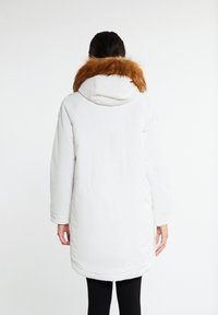 White long parka with a hood, featuring a detachable brown faux fur collar. Smooth texture, relaxed fit, and side pockets.