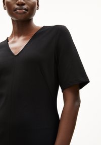 Schwarzes V-Ausschnitt-Kleid mit kurzen Ärmeln, aus einem glatten Stoff gefertigt, mit körperbetontem Design und dezenten Nähten an den Säumen.