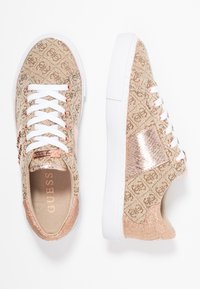 Béžové vzorované tenisky s bílými tkaničkami, růžově zlatými detaily a texturovanými stranami. Mají bílou gumovou podrážku a lesklý povrch.