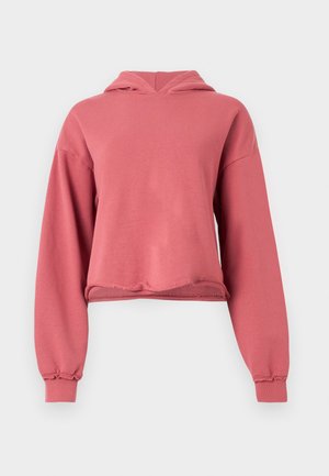 Poros rózsaszín, rövidített kapucnis pulóver hosszú ujjakkal, bordás mandzsettákkal és nyers szegéllyel, egyszerű világos háttéren.