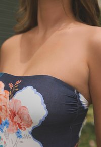 Šaty bez ramínek s tmavě námořnickou látkou a květinovými vzory v růžové a modré barvě. Texturovaný design se nařasenými detaily v oblasti dekoltu.