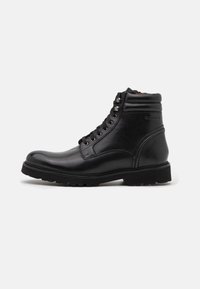 Bottines noires en cuir avec un bout rond, des œillets en métal et une semelle en caoutchouc robuste avec un motif texturé pour une meilleure adhérence.