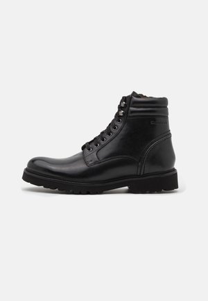 Bottines noires en cuir avec un bout rond, des œillets en métal et une semelle en caoutchouc robuste avec un motif texturé pour une meilleure adhérence.