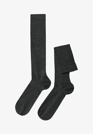 Dunkelgraue knielange Socken aus einem weichen, strukturierten Material. Verfügt über ein glattes Strickdesign und verstärkte Zehen. Eine Socke ist gerollt.
