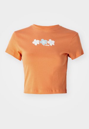 T-shirt orange court en coton avec des manches courtes, décoré de fleurs brodées blanches et bleu clair sur le devant.