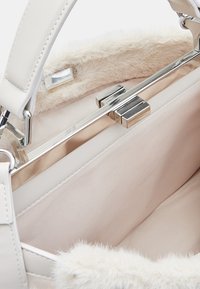 Borsa bianca con morbido bordo in pelliccia sintetica, esterno in pelle liscia, hardware in argento e un ampio interno foderato in satin.