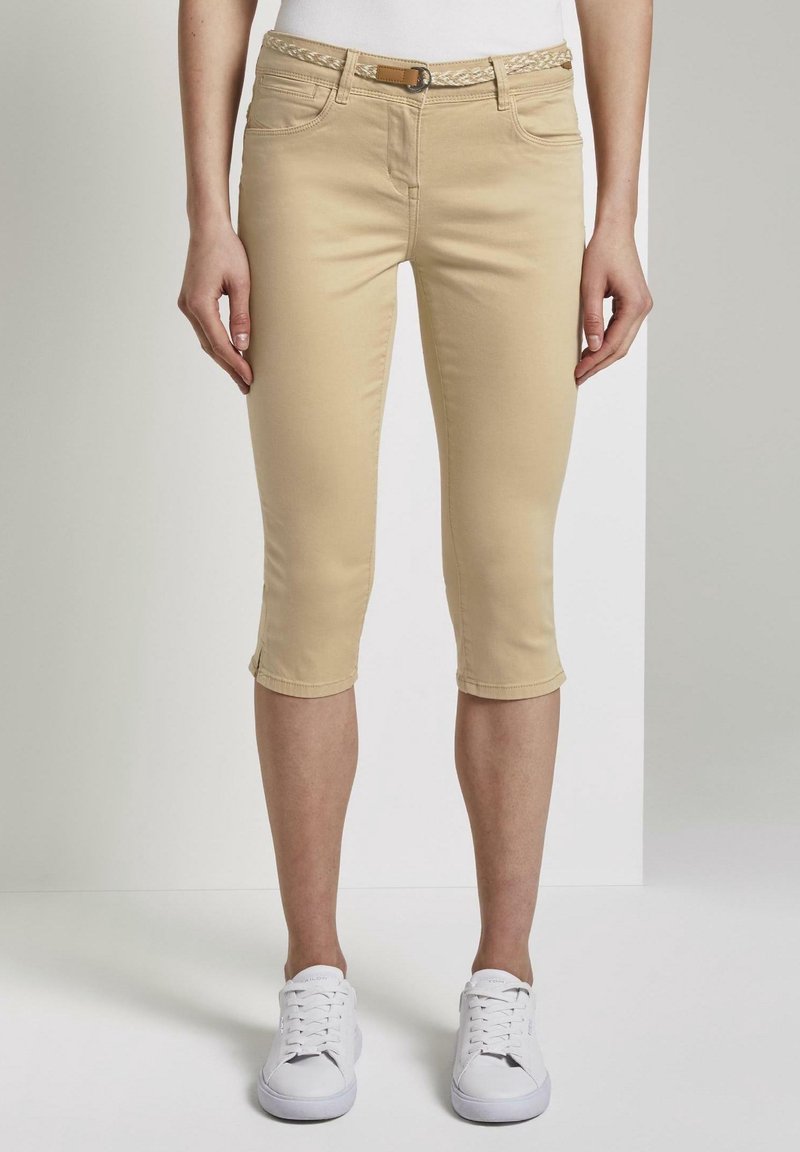Beige capri-broeken van katoenmix, met een gevlochten riem, in een aansluitend ontwerp en met omgeslagen manchetten. Witte sneakers worden gedragen.