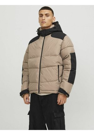 Chaqueta acolchada en beige con acentos negros, presenta un cierre frontal con cremallera, cuello alto y textura acolchada; incluye una capucha ajustable y bolsillos laterales.
