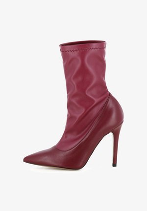Stivale in pelle bordeaux a tacco stiletto con punta affusolata e texture leggermente stropicciata sulla gamba.