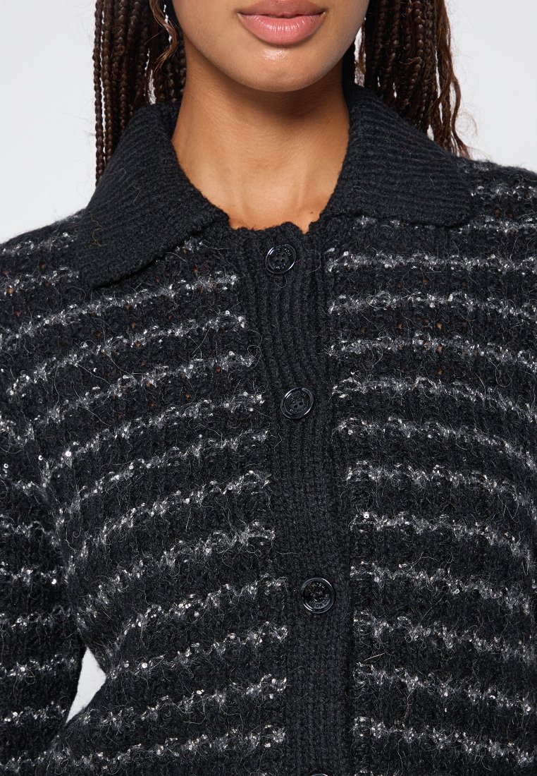 Zwarte gebreide cardigan met een kraag, horizontaal gestreept patroon en zwarte knopen. Zachte textuur met enkele metallic accenten.