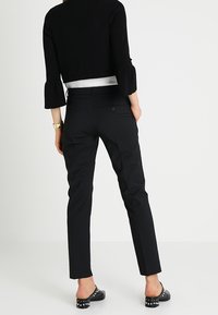 Černý krátký svetr s rukávy do tří čtvrtin, doplněný o černé společenské kalhoty s úzkým střihem a detailem zadní kapsy. Černé baleríny s cvočky.