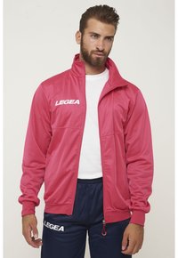 Rosa sportjacka med hög krage och dragkedjestängning. Har en vit logotyp "LEGEA" på bröstet och matchande ärmslut. Slät, lättviktig material.