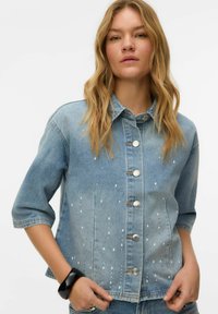 Gaiši zila džinsa jaka ar trīs ceturtdaļas garuma piedurknēm, sudraba pogu aizdari un ūdens pilienu rakstu priekšpusē. Teksturēts audums.