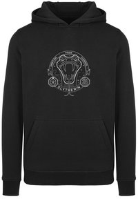 Juoda striukė su sidabriniu Slytherin logotipu, vaizduojančiu gyvatę, aplink ją esantis tekstas "Ambicija", "Pondė" ir "Apsukrumas", su priekiu kišenė.
