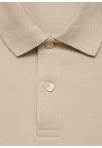 Beige polo skjorte med struktureret stof, klassisk krave og en enkelt knaplukning med en glat finish.