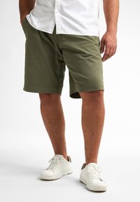 Oliwkowe szorty w casualowym designie, wykonane z lekkiego materiału. W połączeniu z białymi sneakersami, krój jest luźny i prosty.