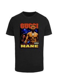 Sort bomulds t-shirt med et grafisk print af to figurer, fed tekst "GUCCi" og "MANE" i gul og rød med en farverig baggrund.