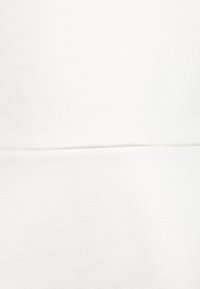 Texture de tissu blanc avec une couture horizontale traversant le centre, montrant des détails fins du matériau tissé.