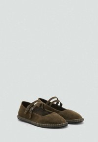 Zapatos planos de ante marrón con correas de doble hebilla y suelas de goma cosidas, mostrados uno al lado del otro sobre un fondo claro.