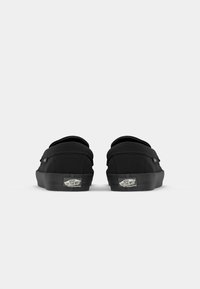 Sorte lerret slip-on sko med en glatt tekstur, rund tå, polstret krage og gummisåle med logo på hælen.