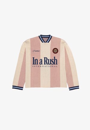 Tricou de rugby cu mâneci lungi, cu dungi verticale late crem și roz, guler și manșete cu dungi bleumarin și inscripția „In a Rush International” imprimată pe față.