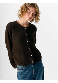 Brun stickad cardigan med långa ärmar, rund halsringning, framfickor och knappar i guldton. Texturerad, mjuk tyg, avslappnad passform.