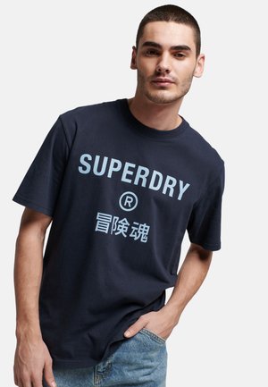 T-shirt in cotone navy con logo "SUPERDRY" bianco e caratteri cinesi, maniche corte, colletto tondo, vestibilità comoda e design semplice.