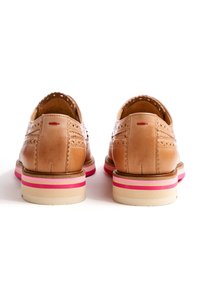 Tan leather shoes with intricate broguing, rounded toe, and a multicolored striped sole featuring pink and cream accents.