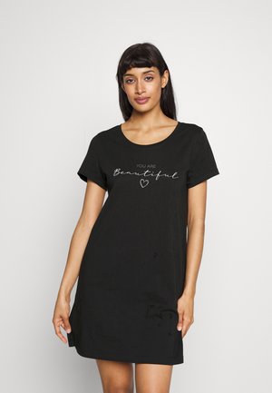 Schwarzes T-Shirt-Kleid aus weicher Baumwolle mit relaxed Fit. Mit einem runden Ausschnitt und weißem Drucktext: "DU BIST schön" mit einem Herz.